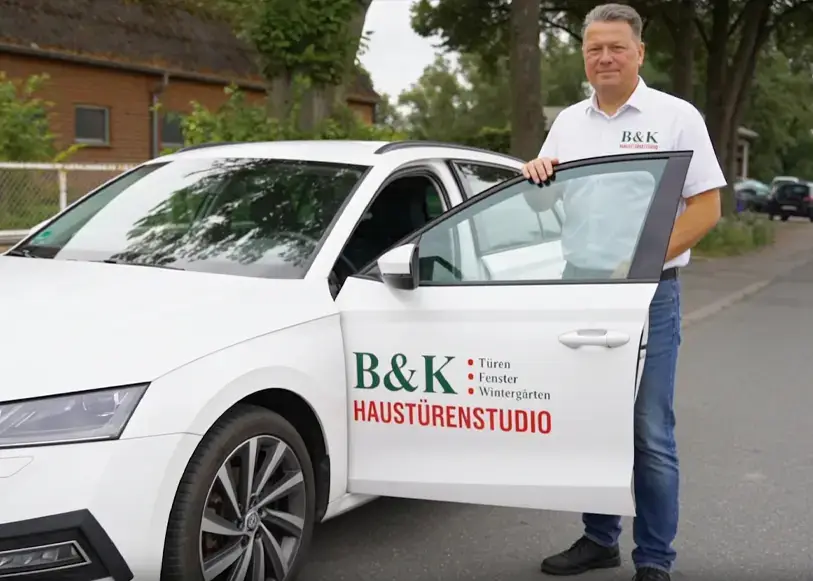 Vertriebsmitarbeiter von B & K Knoop Haustürenstudio aus Nusse vor einem Firmenfahrzeug im Außendienst für Haustüren, Fenster und Wintergärten in der Region Lübeck, Mölln, Geesthacht und Hamburg.